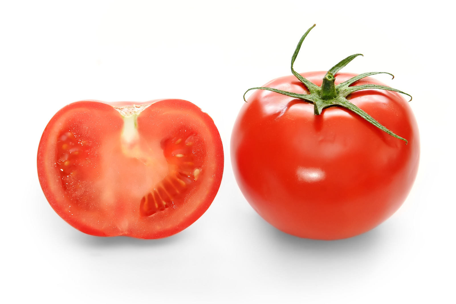 A whole red tomato beside a tomato cut in half, showing the seed chambers
